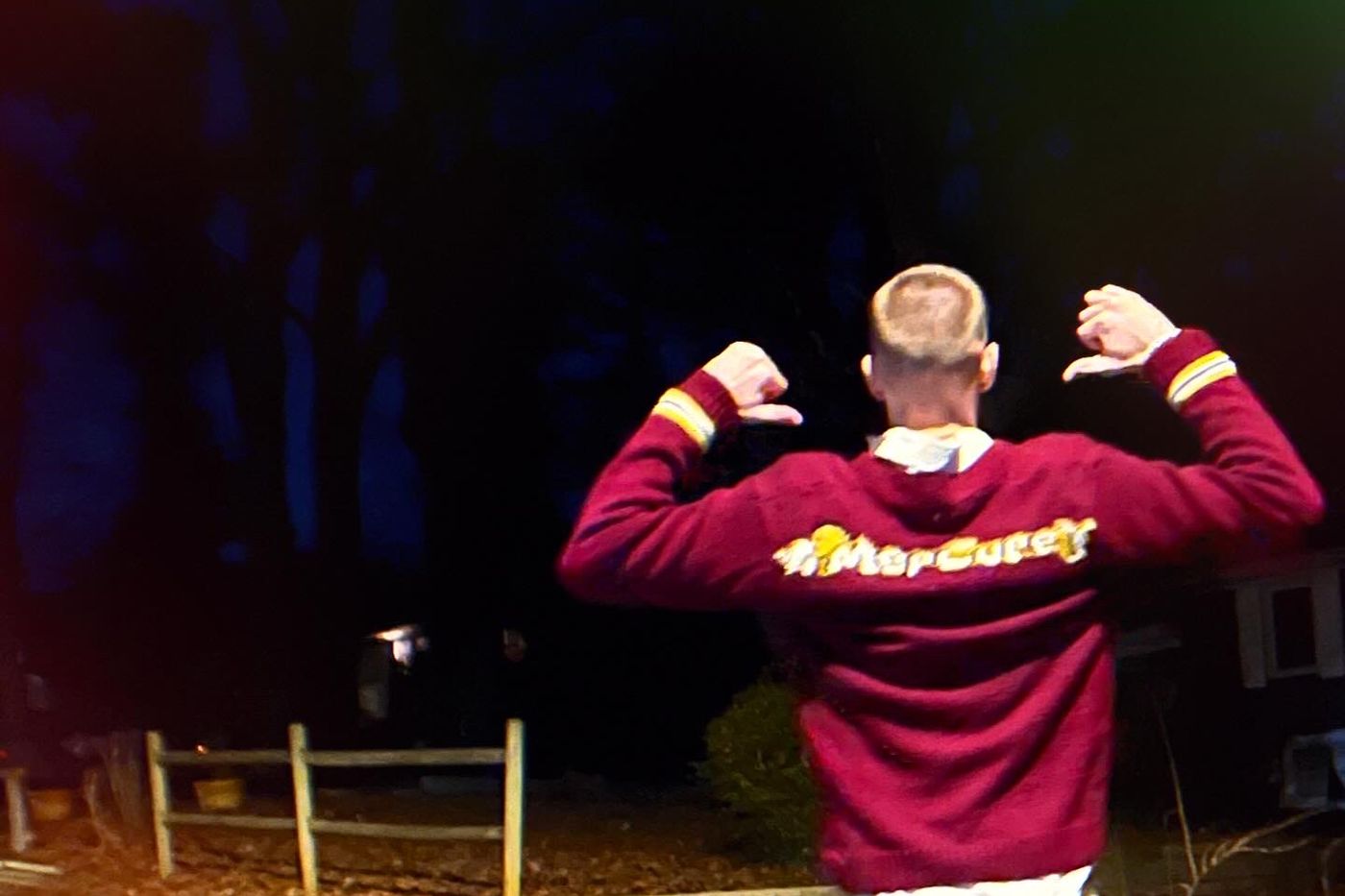 MerCureY wearing a MerCureY cardigan, photographed from behind at night
